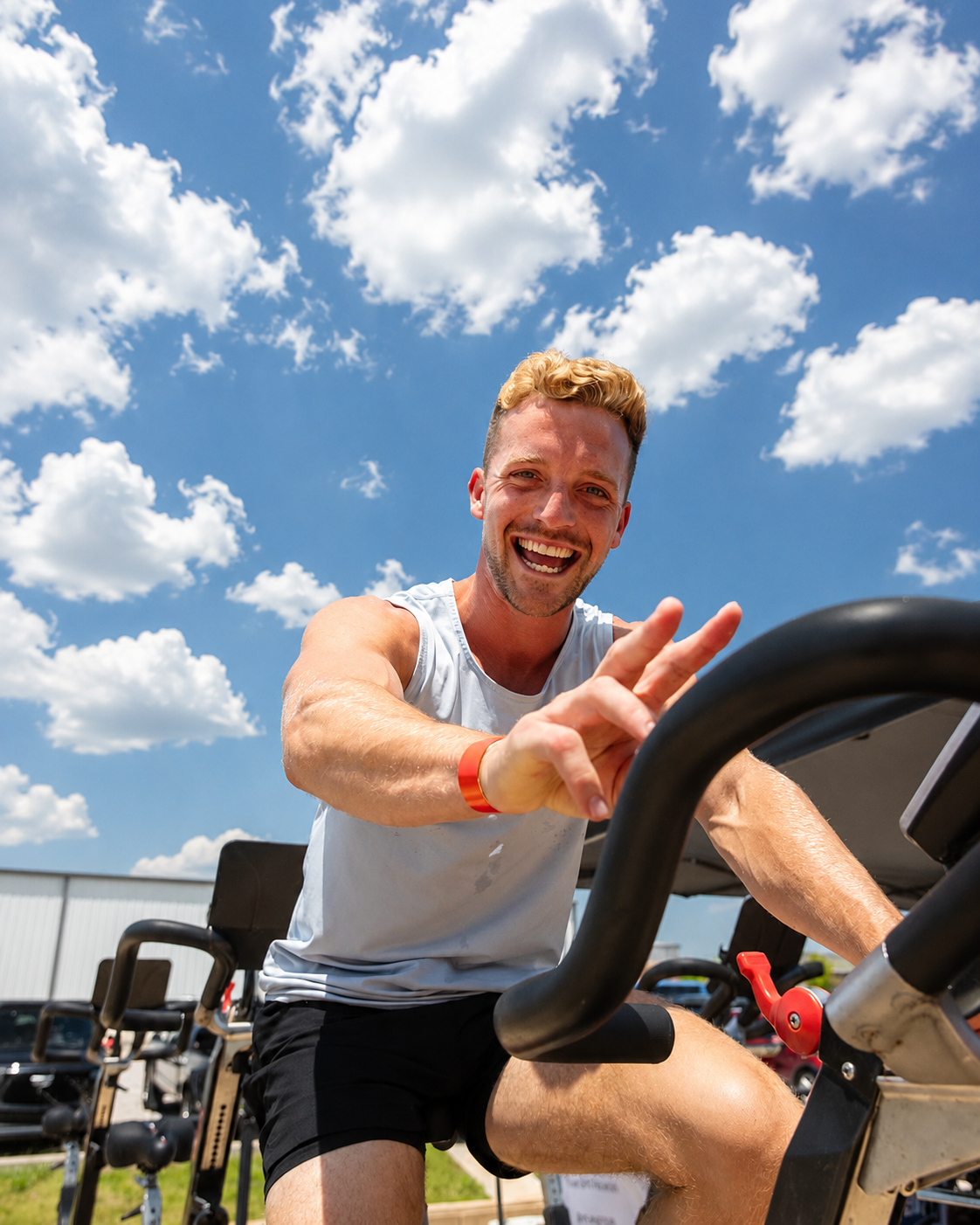 A True Grit Fitness member smiling on a stationary bike during an outdoor class